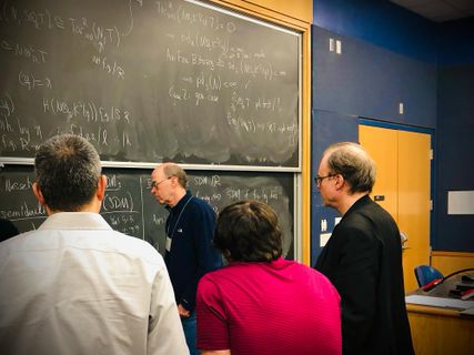 Group of 3 discuss an algebra problem at the chalkboard