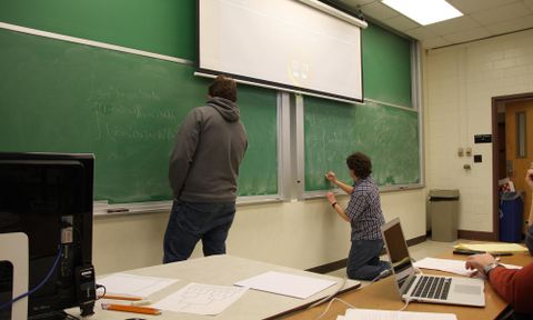 Students in math class work at the chalkboard